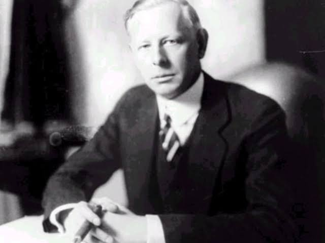 Jesse Livermore seated at his desk with cigar, formal suit